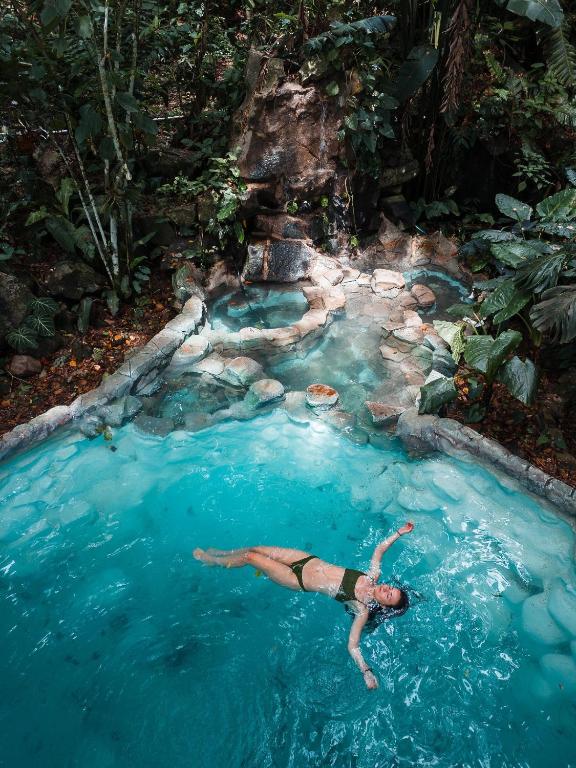 Piscina natural de piedra rodeada de bosque tropical en el retiro de bienestar de Cerro Tusa Springs en Venecia, Antioquia